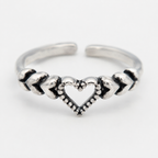 A close up of silver-toned toe ring featuring a central open heart design with textured chevron details on either side, photographed on a clean white background.