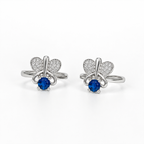 A pair of silver butterfly stud toe rings, each featuring a round blue sapphire at the center and pavé-set clear stones in the wings, shown on a clean white background.