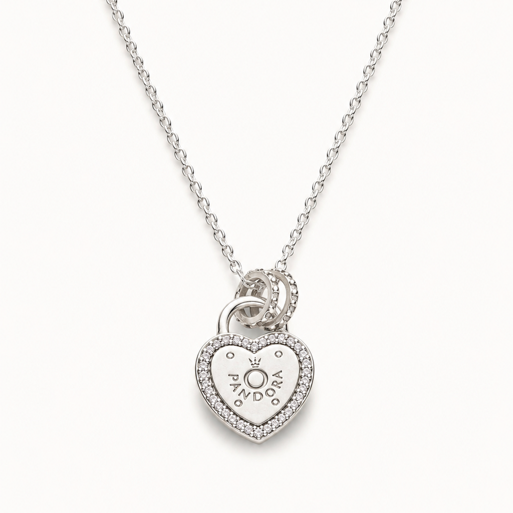 A silver heart-shaped pendant necklace with a small heart and sun motif in the center, surrounded by a border of tiny clear stones, hanging from a delicate silver chain against a light off-white background.
