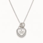 A silver heart-shaped pendant necklace with a small heart and sun motif in the center, surrounded by a border of tiny clear stones, hanging from a delicate silver chain against a light off-white background.
