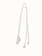 A delicate silver chain necklace featuring a small light pink pearl pendant and a silver safety pin clasp, displayed on a clean white background.