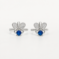 A pair of silver-tone toe rings featuring a butterfly design with pavé-set clear stones and a central round blue gemstone, shown on a plain light background.