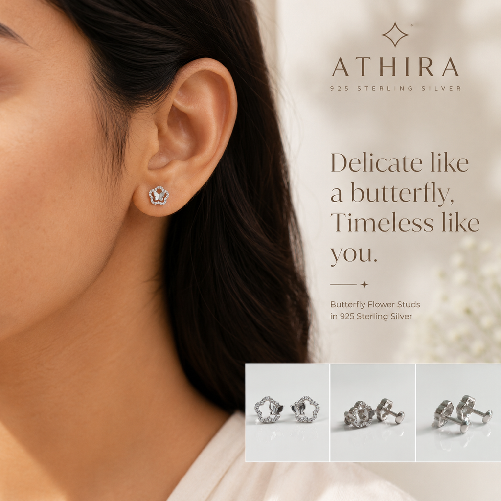 A close-up of a woman's ear wearing a small silver butterfly stud earring, with the brand name ATHIRA and product text 'Delicate like a butterfly, Timeless like you.' on a soft light background.