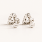 A pair of silver heart-shaped stud earrings with a textured, pave-like surface and a round disc back engraved with 'S925', shown on a clean white background.