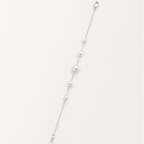 A delicate silver chain bracelet featuring a graduated sequence of white pearls, displayed diagonally on a clean white background.
