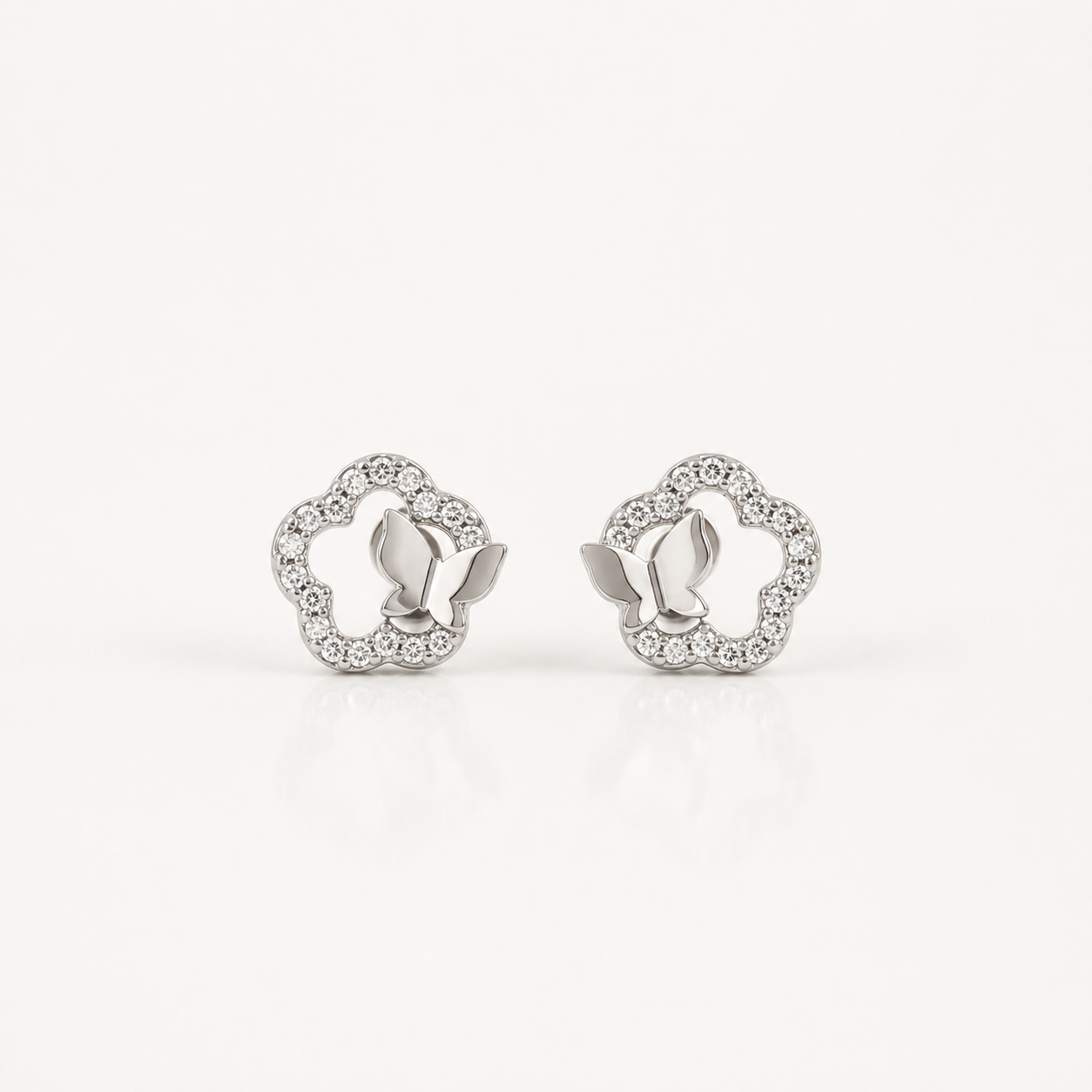 A pair of silver-toned butterfly stud earrings with a delicate border of small clear stones, displayed on a clean white background.