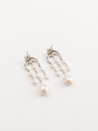 A pair of silver-tone drop earrings featuring curved filigree tops, small pearl beads, and larger pear-shaped pearls hanging at the ends, displayed on a clean white background.