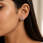A close-up of a woman's ear wearing a small heart-shaped stud earring with a silver-tone outline and clear stones.