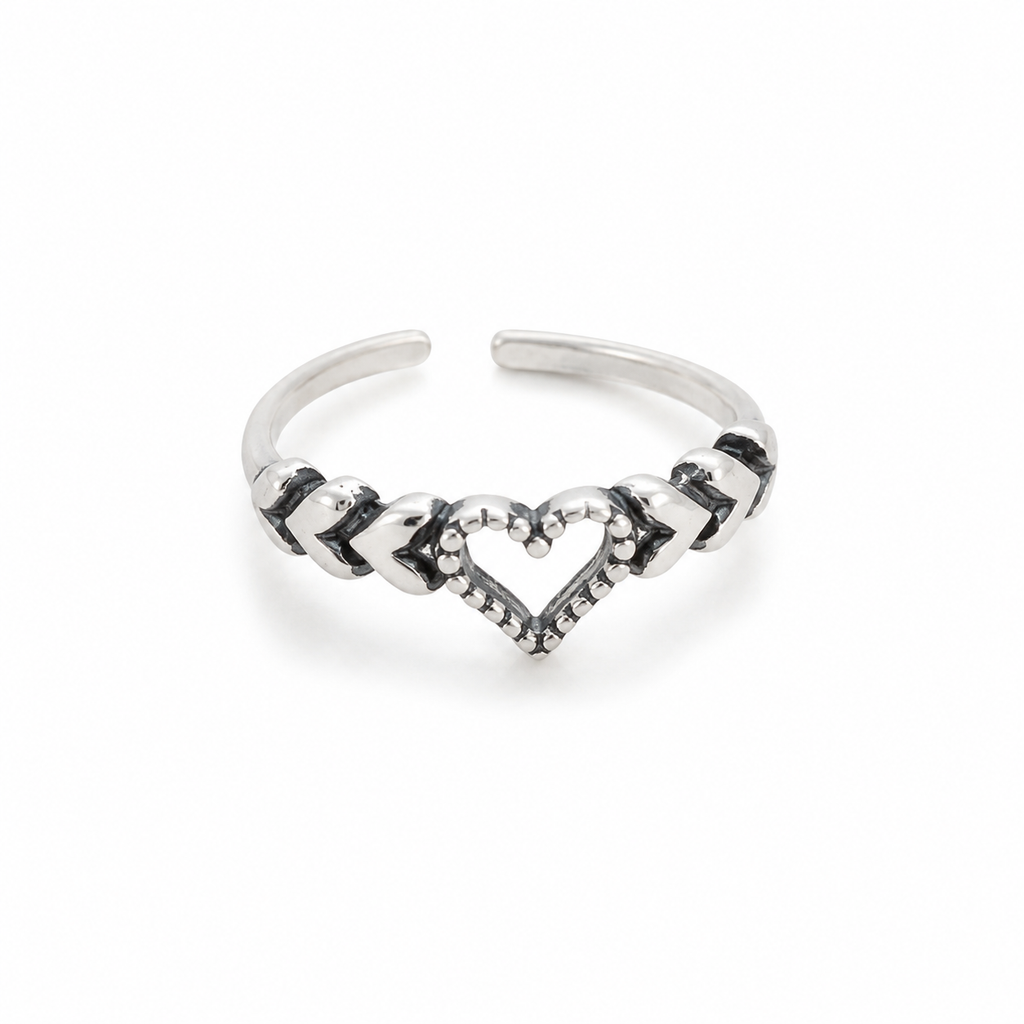 A silver-toned toe ring featuring a central heart design with small clear stones and alternating polished and textured chevron details, shown on a plain white background.